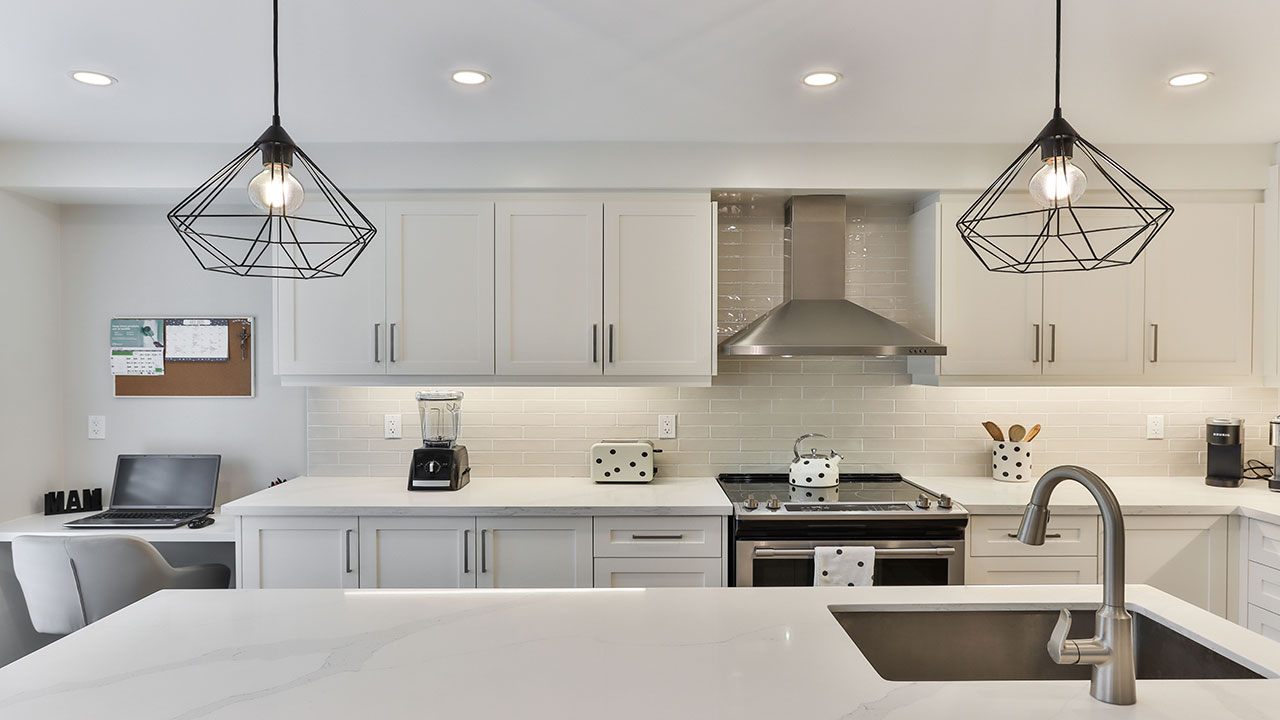 Modern kitchen with white kitchen cabinets, marble countertops, stainless steel appliances, and pendant lighting. Modern kitchen with white kitchen cabinets, marble countertops, stainless steel appliances, and pendant lighting.