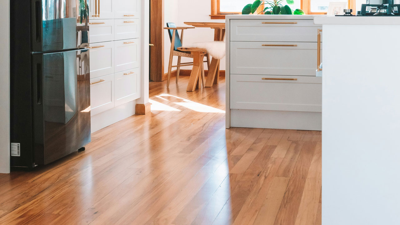 Bright kitchen with white kitchen cabinets and warm wooden floors, featuring modern brass hardware and natural light. Bright kitchen with white kitchen cabinets and warm wooden floors, featuring modern brass hardware and natural light.