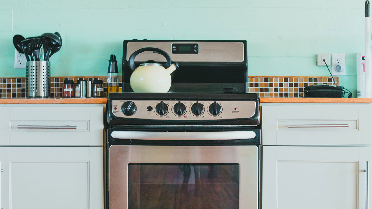 Retro kitchen with white kitchen cabinets, wooden countertop, stainless steel stove, and cooking utensils on the counter. Retro kitchen with white kitchen cabinets, wooden countertop, stainless steel stove, and cooking utensils on the counter.