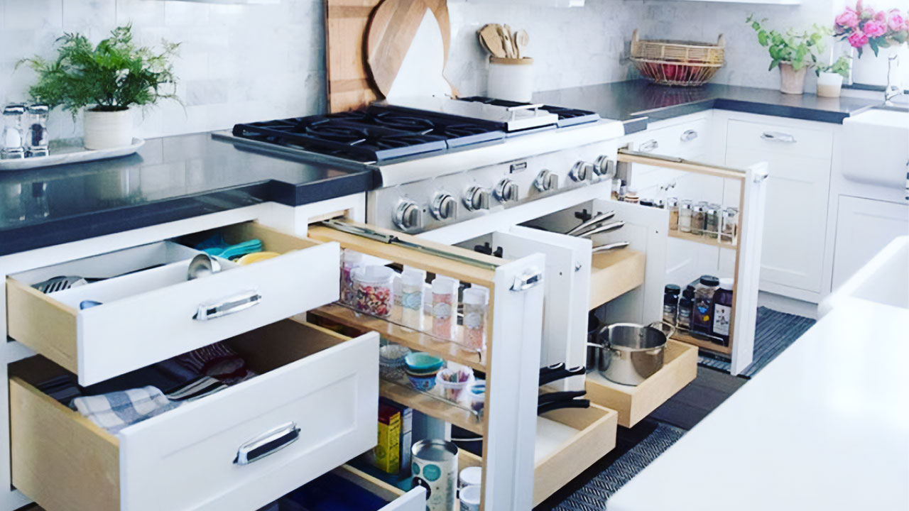 Organized kitchen with white kitchen cabinets, pull-out drawers, and modern black countertops around a stainless steel stove. Organized kitchen with white kitchen cabinets, pull-out drawers, and modern black countertops around a stainless steel stove.