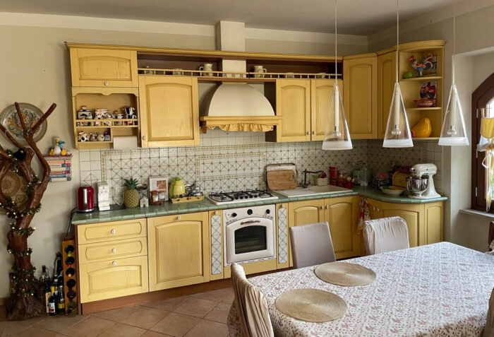 Dining table with tablecloth in the center of a muted yellow kitchen