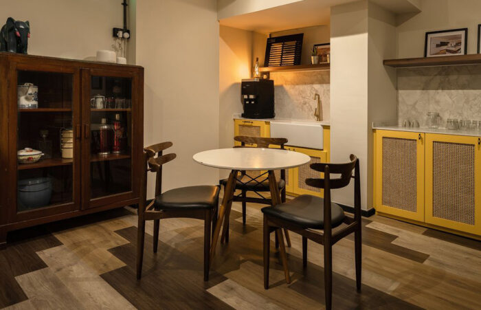 Dining table with chairs opposite bright yellow cabinets with cane rattan detailing