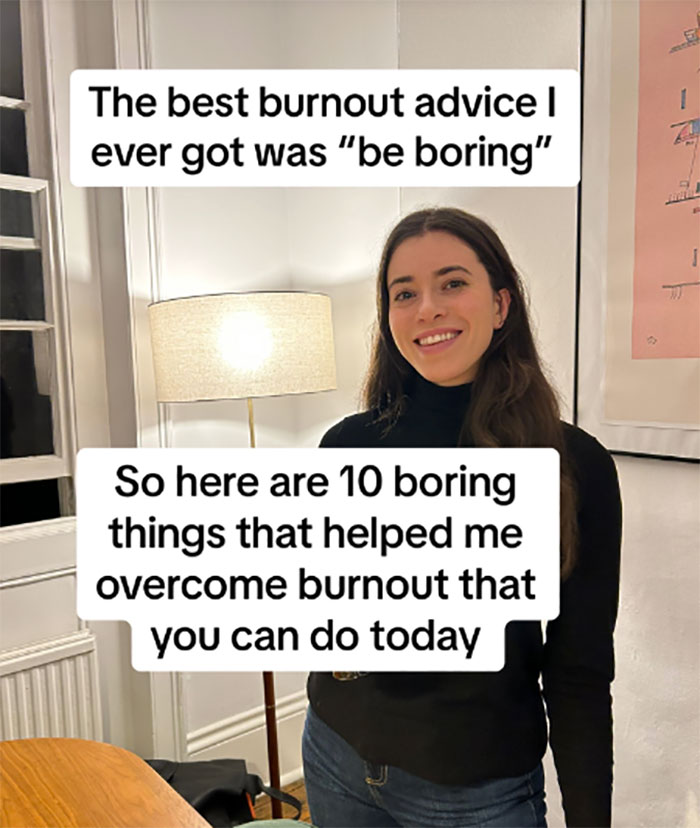 Woman sharing burnout advice about being boring, smiling in a cozy room with a lamp and wall art.