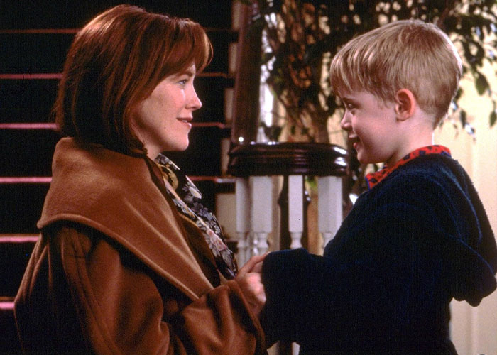 "Home Alone" scene with Kevin's mom, portrayed by Catherine O&rsquo;Hara, at 36, holding hands with her son on a staircase.