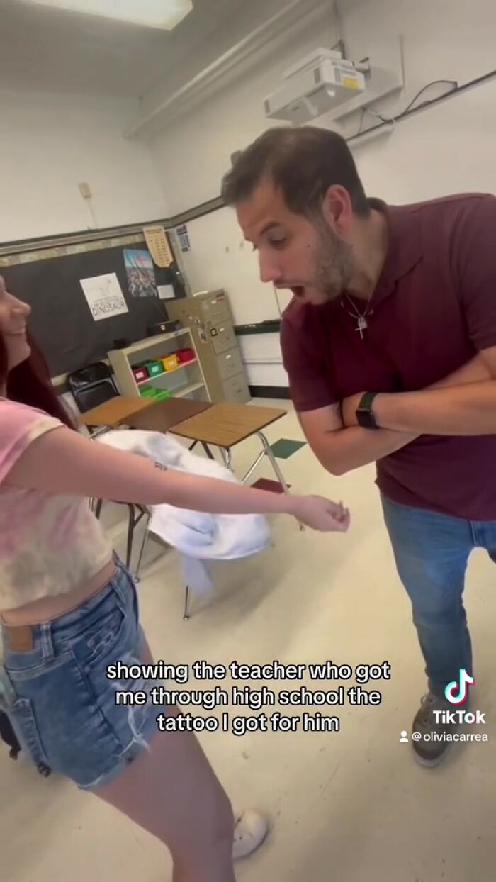 Student showing tattoo of teacher's handwritten note in a classroom, with teacher reacting in surprise.
