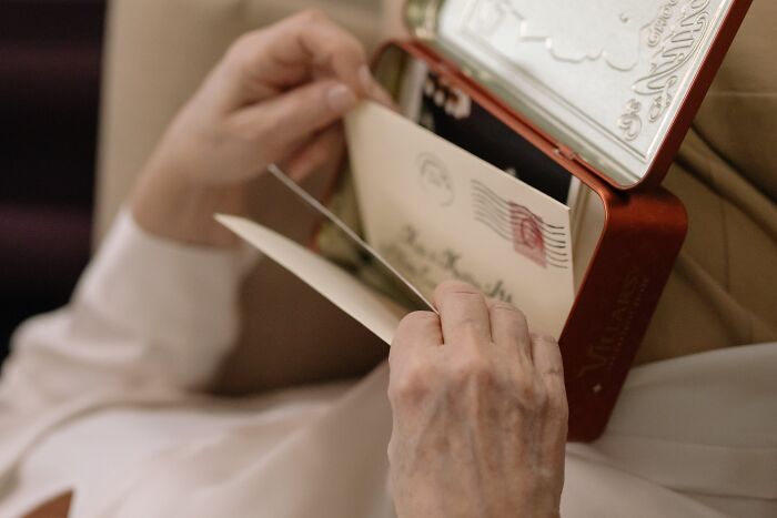 Hands opening a small tin box with old letters inside, illustrating weird surprises found after moving into a new home.