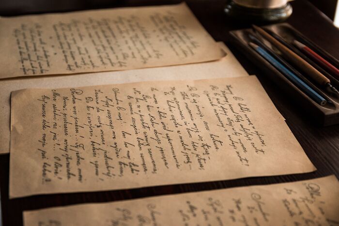 Old handwritten letters on a wooden table with a pen set, illustrating weird surprises people found after moving into a new home.