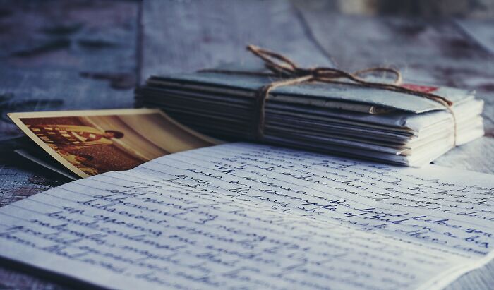 Stack of old letters and a vintage photo on a wooden table, representing weird surprises found after moving into a new home.