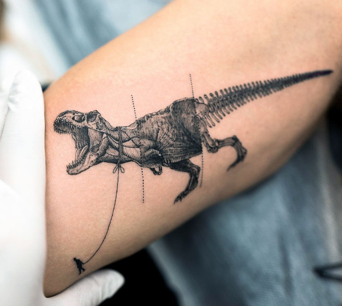 Cool dinosaur tattoo of a Tyrannosaurus rex on an arm, with intricate black ink details and creative design.