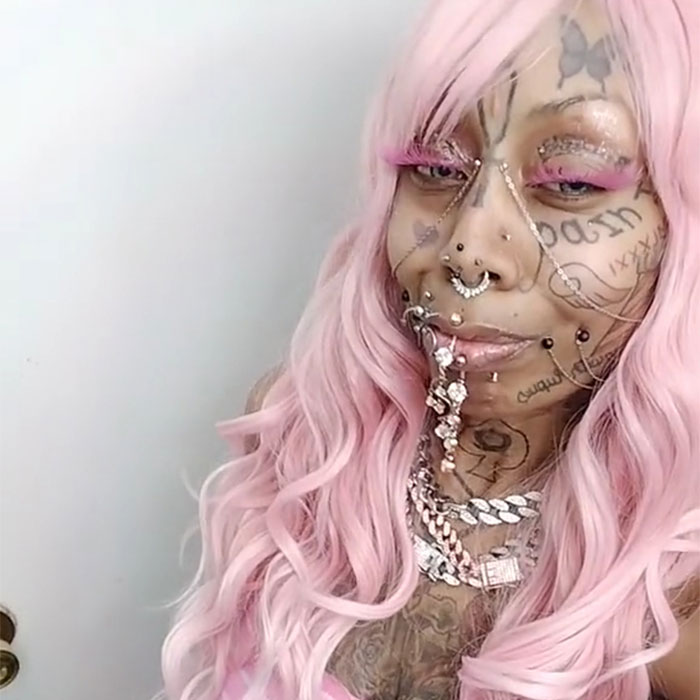 Inked grandmother, 41, with pink hair and facial tattoos, confidently embraces her unique look, defying online criticism.