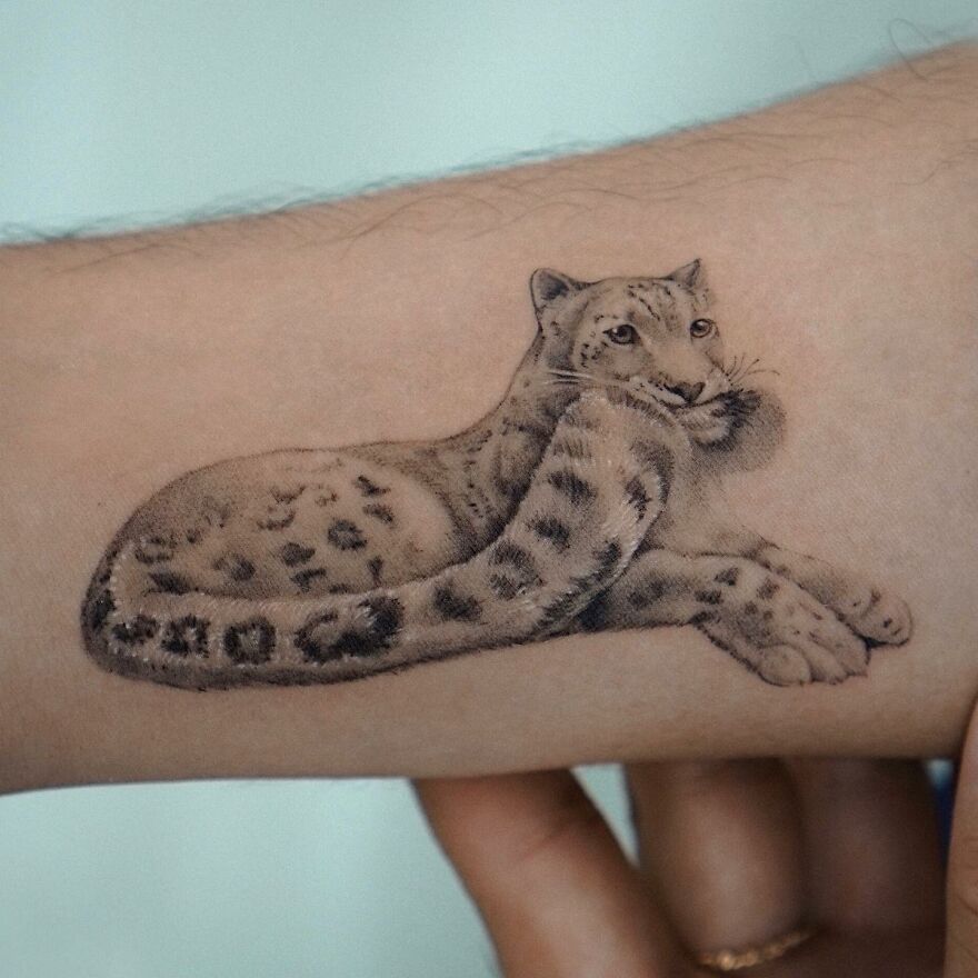 Tattoo of a snow leopard, resembling a painting, by Korean ink artist, blending nature and animals.