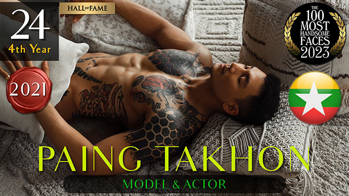 Model Paing Takhon on a couch, showcasing tattoos, featured among the most handsome men in 2023 rankings.