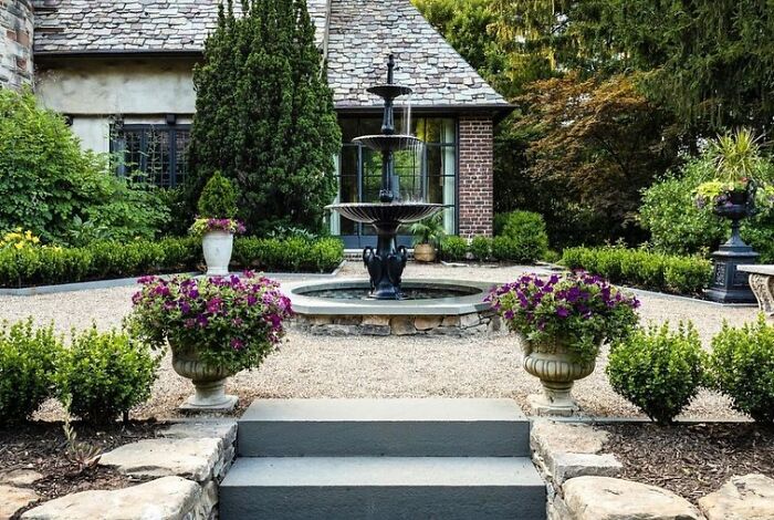 Chic backyard with a multi-tiered fountain as a focal point surrounded by flowers and greenery for stylish outdoors.