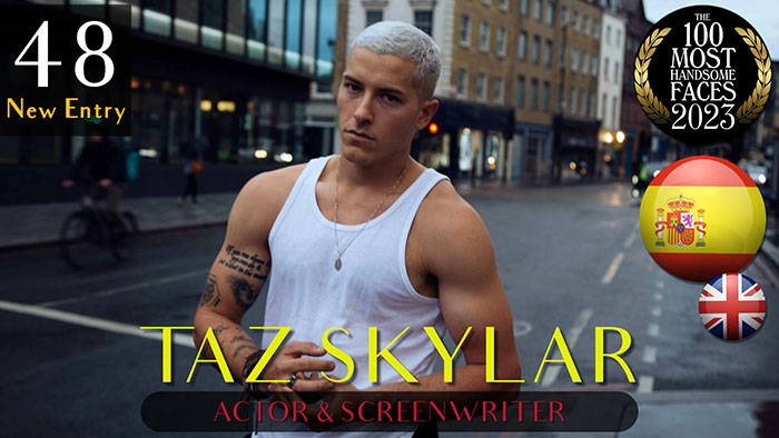 Actor in a white tank top on a city street, ranked among the most handsome men of 2023 by critics.