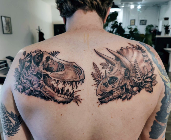 Back displaying a cool dinosaur tattoo design featuring detailed T-Rex and Triceratops skulls.