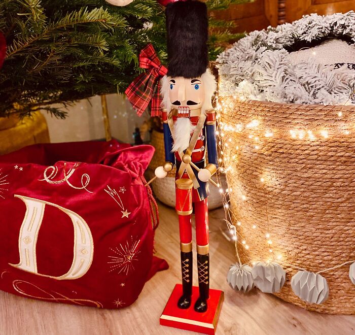 Nutcracker figurine beside a Christmas tree and affordable Christmas decor with festive lights and holiday accents.