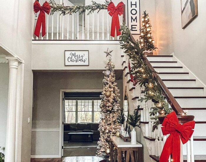 Staircase decorated with evergreen garlands and red bows showcasing affordable Christmas decor ideas for 2024.