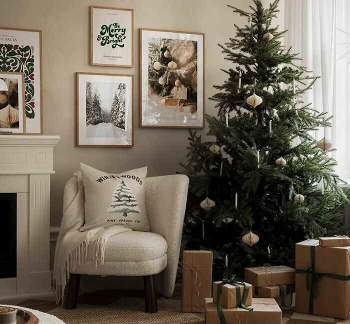 Cozy armchair with pillow and cover near Christmas tree and wrapped gifts, showcasing affordable Christmas decor ideas.