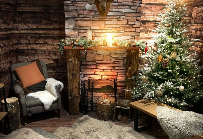 Cozy living room with affordable Christmas decor featuring a grey rug, decorated tree, and rustic fireplace.