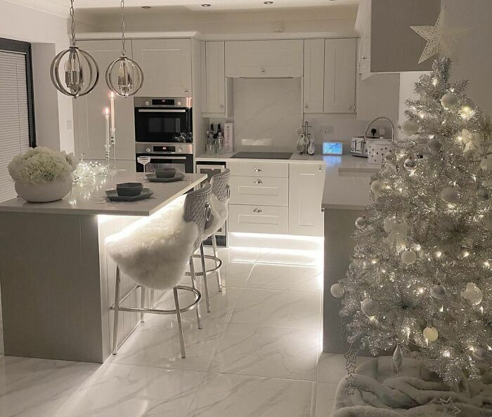 Silver Christmas tree with lights and ornaments in a modern kitchen showing affordable Christmas decor ideas for 2024.