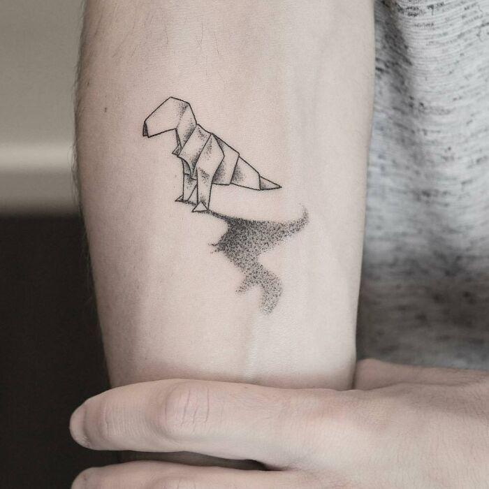 3D tattoo of origami dinosaur with shadow, showcasing tattoo artists' creativity.