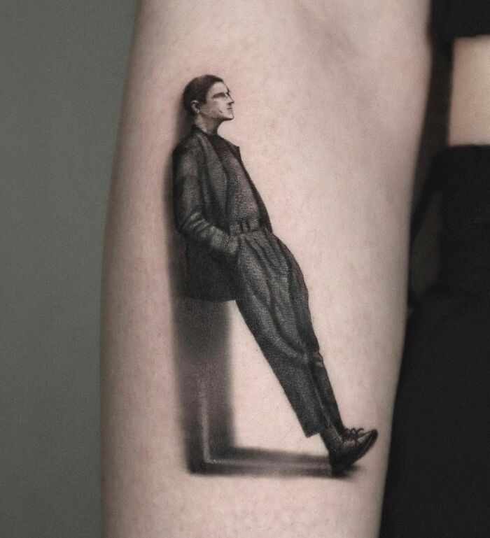 3D tattoo of a man leaning against an invisible wall, showcasing intricate shading and realism on an arm.