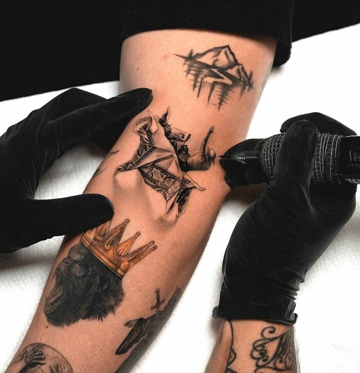 Tattoo artist creating 3D tattoos on an arm with intricate designs and details.