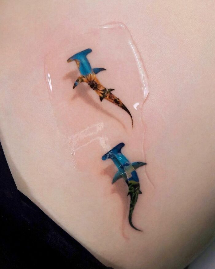 3D tattoo of two realistic hammerhead sharks on skin, highlighting artistic skill and depth.