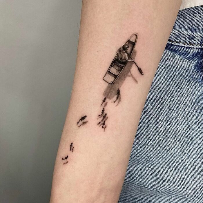 3D tattoo of a small boat with rower on an arm, showcasing intricate details and shadow effects.