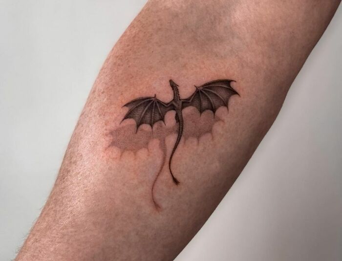 3D tattoo of a dragon on forearm, showcasing realistic detail and shading.