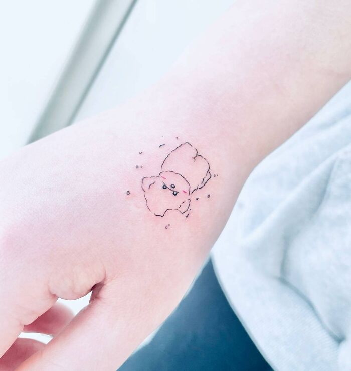 Small hand tattoo of a cute animal design on wrist, emphasizing minimalist style.
