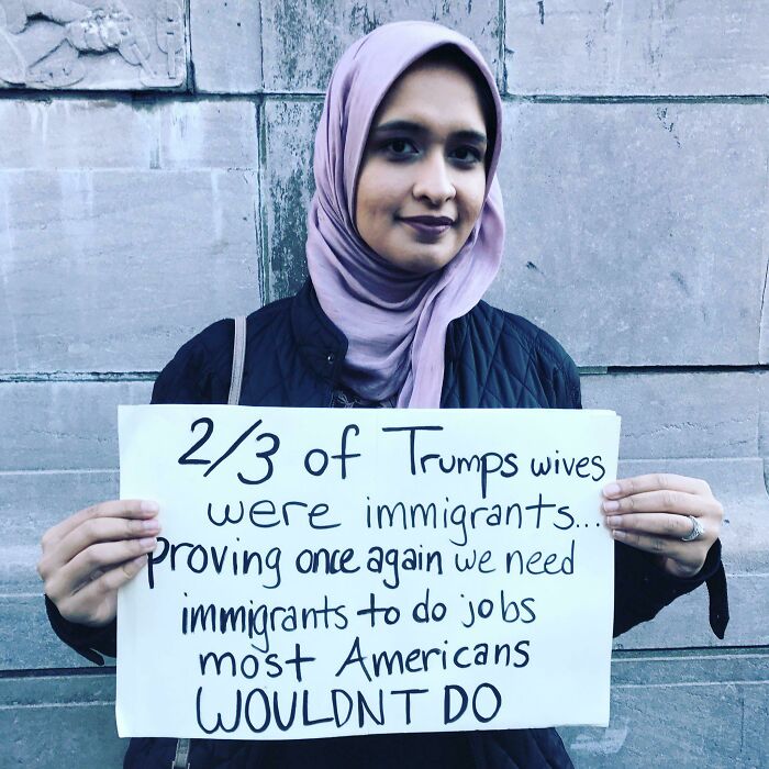 Person holding a humorous meme sign about immigration and jobs in America.