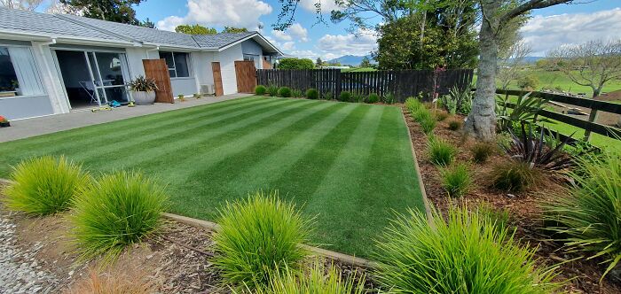 Backyard with perfectly cut grass and neatly landscaped garden beds showcasing chic outdoors with budget-friendly options.