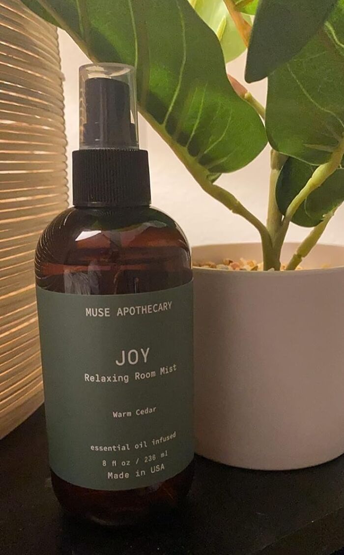 Room mist bottle labeled "Joy" next to a potted plant, ideal for a pre-2025 cleaning mission.