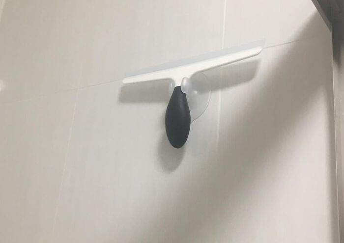 Cleaning tool with a black handle on a white wall, ideal for your pre-2025 cleaning mission.