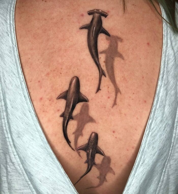 "Spine tattoos featuring realistic shark designs on a person's back."
