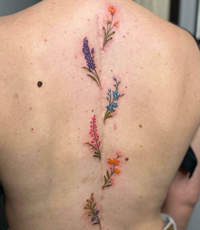 Floral spine tattoo featuring colorful flowers along a person's back.