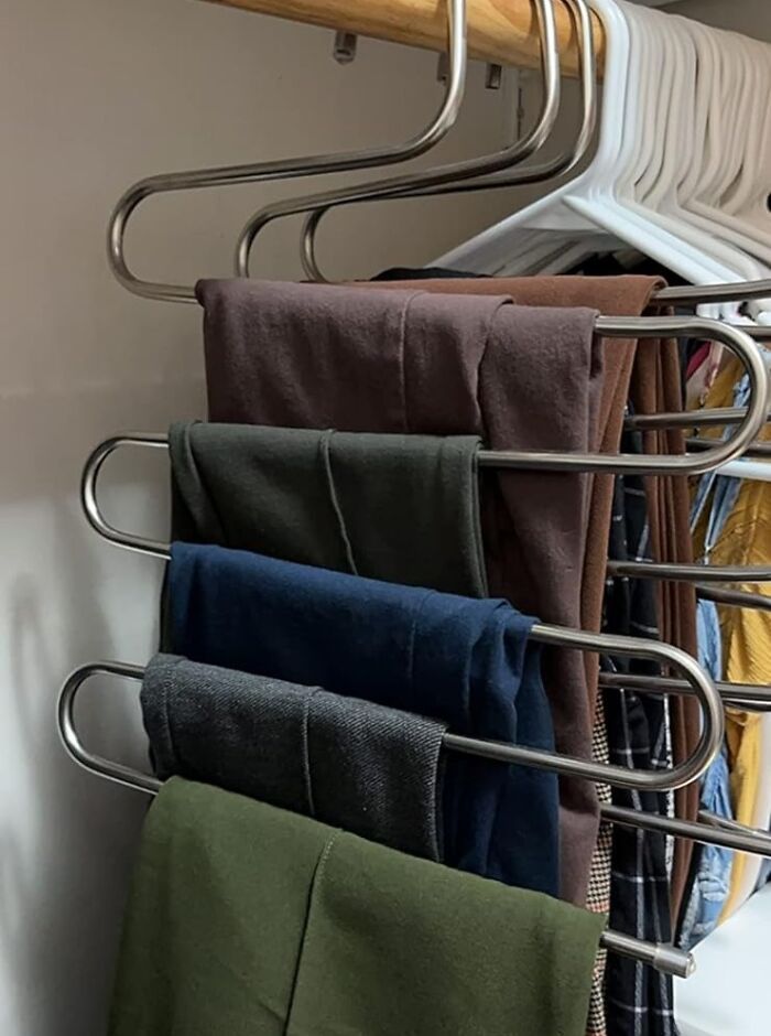Multi-tier hanger for declutter and organise, neatly holding assorted pants in a wardrobe.