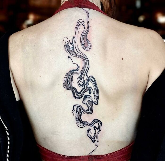 Abstract spine tattoo with swirling black lines, centered on back.