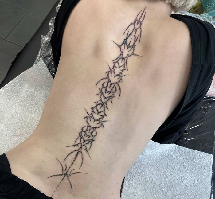 Intricate spine tattoo design showcasing detailed floral and thorn patterns along the back.
