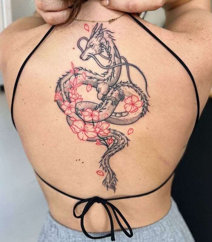 Dragon spine tattoo with cherry blossoms on a person's back, featuring intricate detailing and vibrant colors.