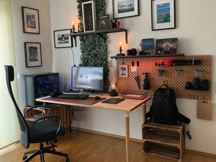 Cozy home office design with wooden desk, ergonomic chair, pegboard organizer, and framed art on white walls.