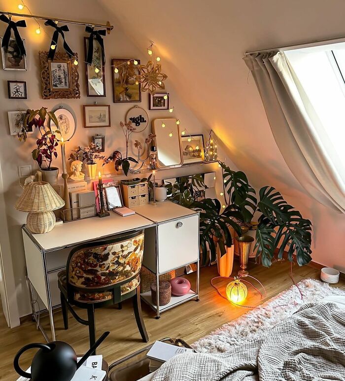 Cozy home office design with warm lighting, plants, and eclectic decor creating a comfortable workspace in a small attic room.