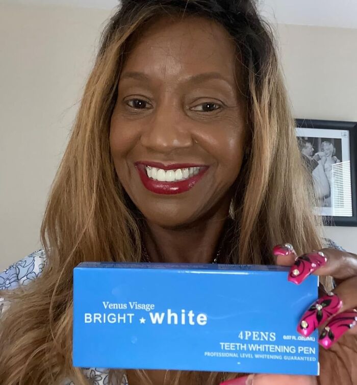 Smiling woman holding a blue Venus Visage Bright White teeth whitening pen, promoting success and goal pursuit.