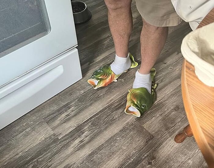 Man wearing fish-shaped slippers, adding humor to everyday life.