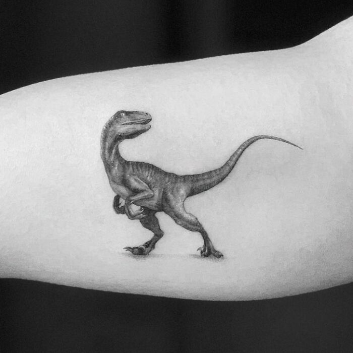 Small, detailed velociraptor tattoo on forearm, showcasing cool dinosaur tattoo idea.