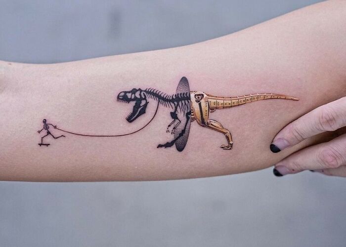 Cool dinosaur tattoo with a T-Rex skeleton and skateboarder, executed on a forearm.