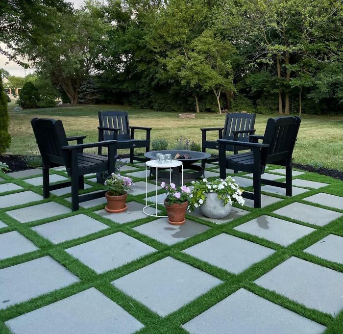 Pavers arranged in a simple backyard patio with black chairs and potted plants creating a chic outdoor space.