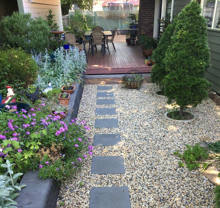 Gravel garden path with stepping stones leading to a porch surrounded by plants for chic outdoor backyard design.