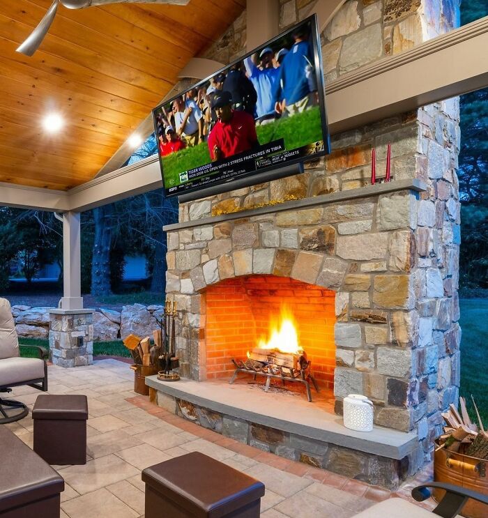 Outdoor fireplace seating area in a backyard showcasing chic outdoors design with cozy fire and stone details.